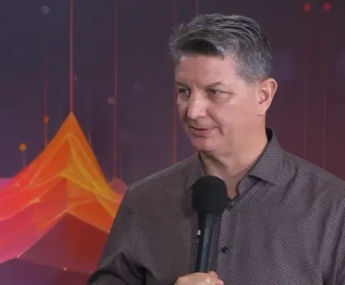 TravelAI CEO John Lyotier speaking into a microphone during a PhocusWire CEO Spotlight interview